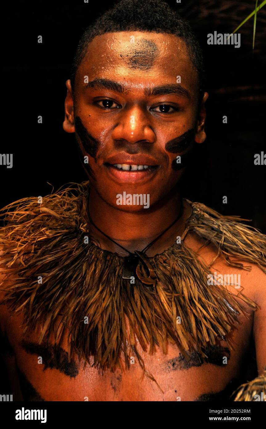 Un jeune homme fidjien avec son visage couvert de marques tribales dans le cadre de sa robe nationale fidjienne. Il participe à une danse traditionnelle fidjienne Banque D'Images