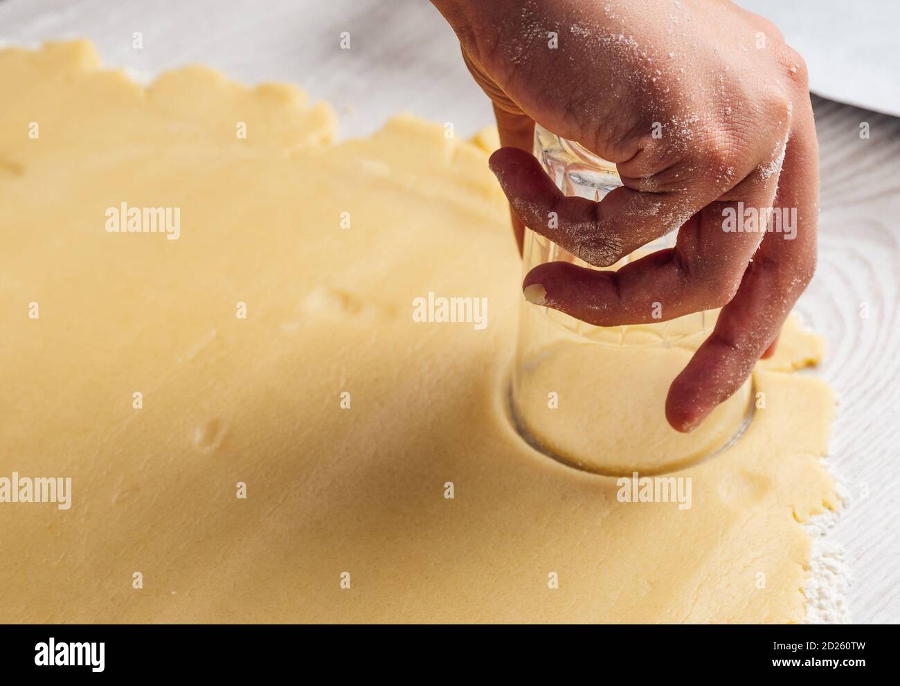 Les mains coupants la pâte à biscuits avec un verre Banque D'Images