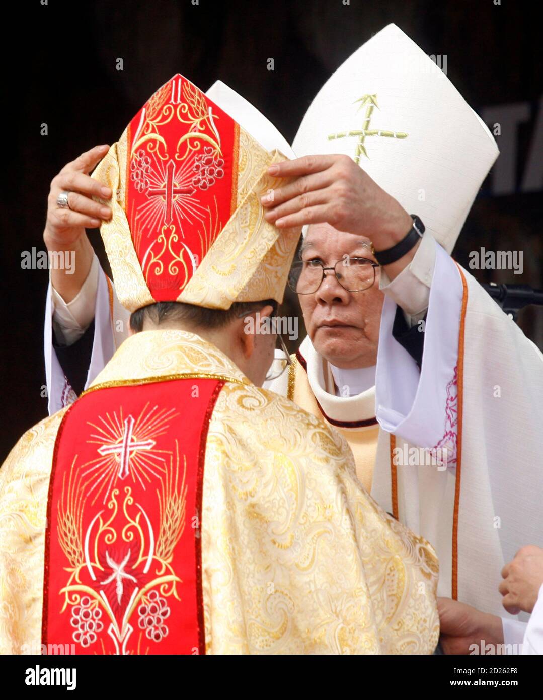 New Hung Hoa diocese's Auxiliary Bishop John Mary Vu Tat (L) receives the bishop's  hat, also know as a Miter, from Hung Hoa Bishop Antoine Vu Huy Chuong  during his consecration ceremony