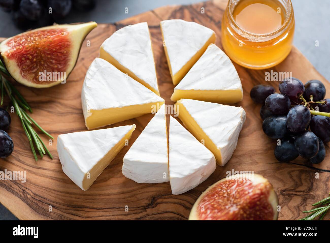 Camembert ou brie avec figues, raisins et miel sur plateau de service en bois. Assiette de fromages Banque D'Images