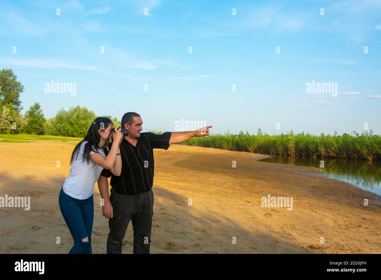 Un père enseigne à sa jeune fille à photographier. Sur la rive du lac, les photographes apprennent à filmer. Banque D'Images