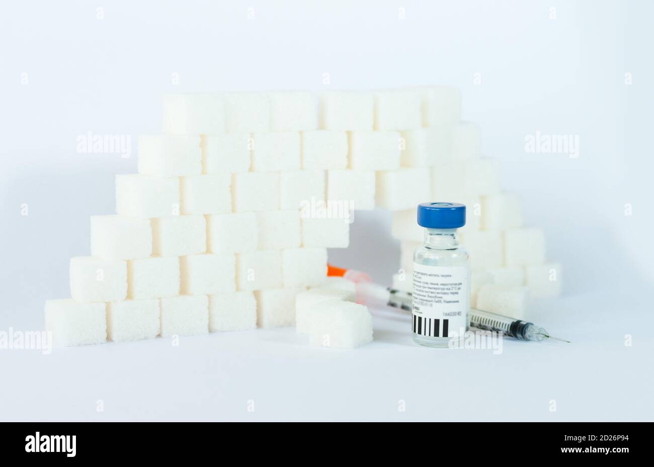 Dépendance au sucre, résistance à l'insuline, régime alimentaire malsain, pyramide des cubes de sucre, bouteilles d'insuline et seringue pour la vaccination sur fond blanc, diabète Banque D'Images