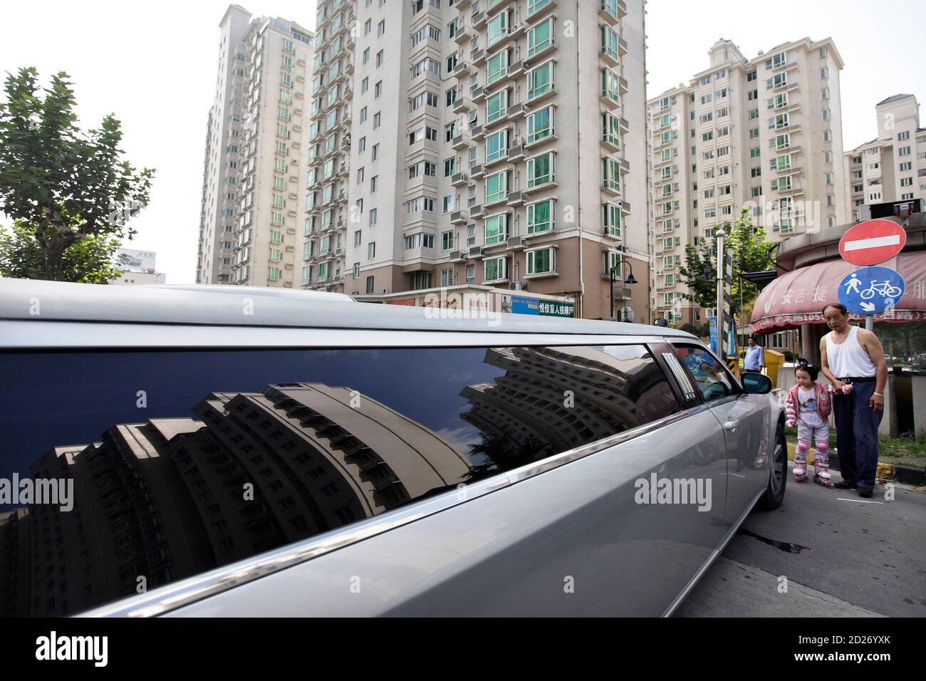 Un homme emmène sa petite-fille pour voir une voiture de limousine Chrysler  pendant qu'il attend de prendre un couple le jour de leur mariage à  Shanghai le 20 septembre 2009. Créé en