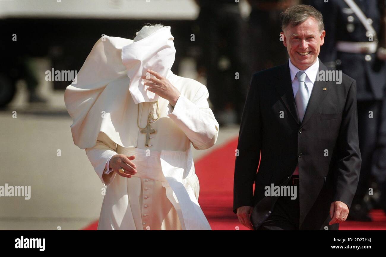 Pope Benedict XVI walks beside German President Horst Koehler as heavy wind  blows his cape into his face after his arrival at Cologne's airport, August  18, 2005. Pope Benedict will face the