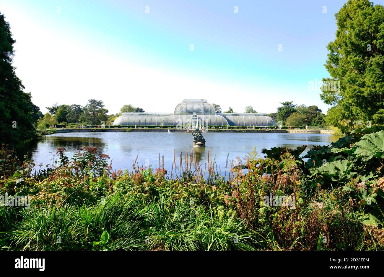 Le Palm House et le lac dans les jardins botaniques royaux, Kew à Richmond sur la Tamise. Banque D'Images