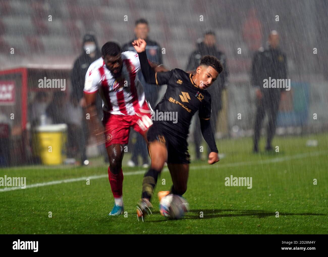 Femi Akinwande de de Stevenage (à gauche) et Matthew Sorinola des Dons de Milton Keynes se battent pour le ballon alors que la pluie tombe pendant le match du Trophée de l'EFL au stade Lamex, à Stevenage. Banque D'Images