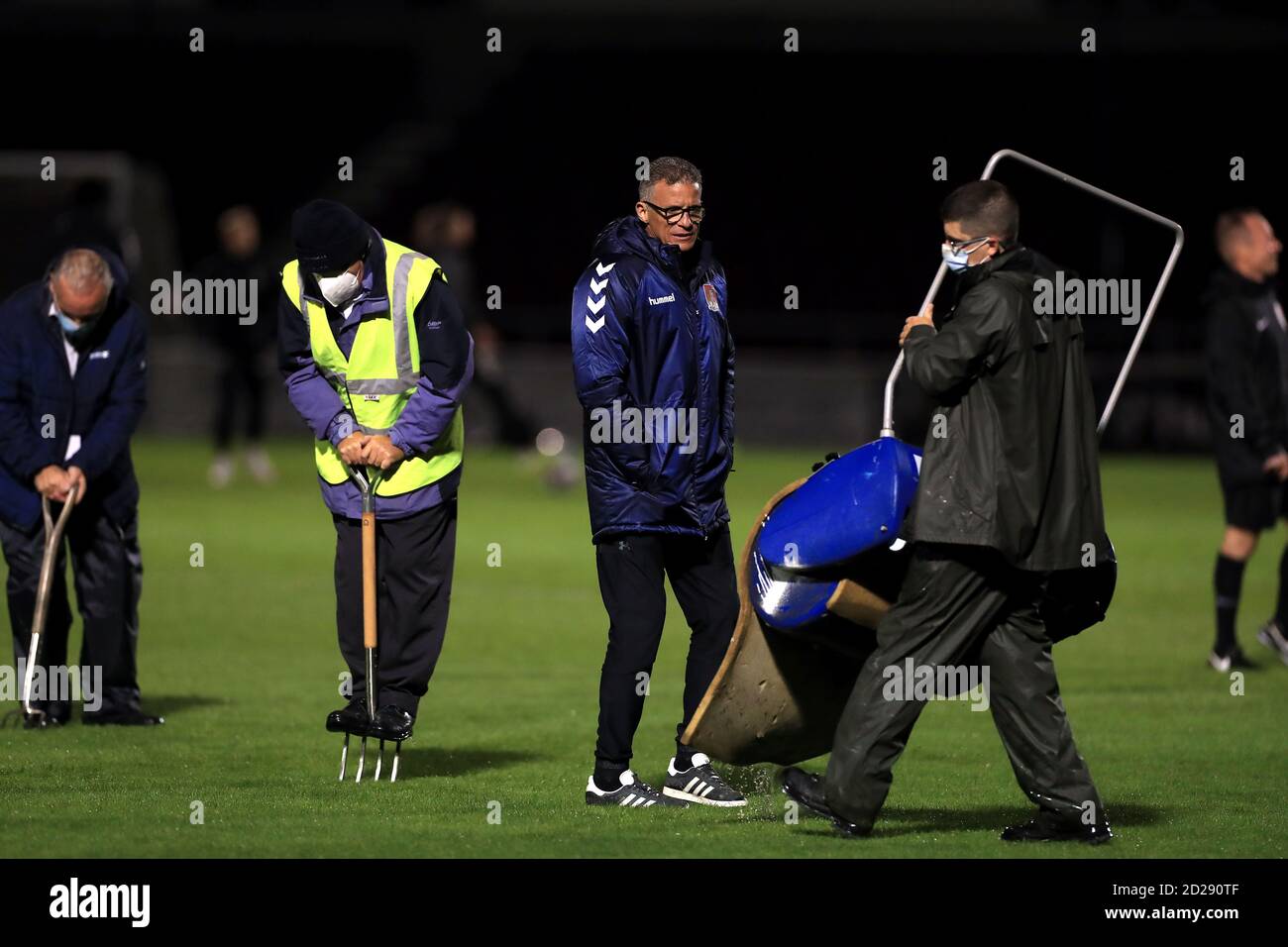 Keith Curle, directeur de la ville de Northampton, aide le personnel au sol avec un rouleau lorsqu'il a tendance à se rendre sur le terrain avant le match du Trophée EFL au PTS Academy Stadium, à Northampton. Banque D'Images