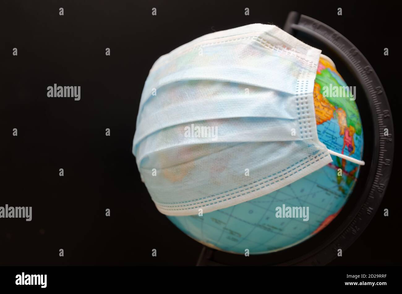 Globe dans un masque médical sur fond noir avec espace de copie. Pandémie mondiale covid-19, coronavirus. Concept de propagation du virus Banque D'Images