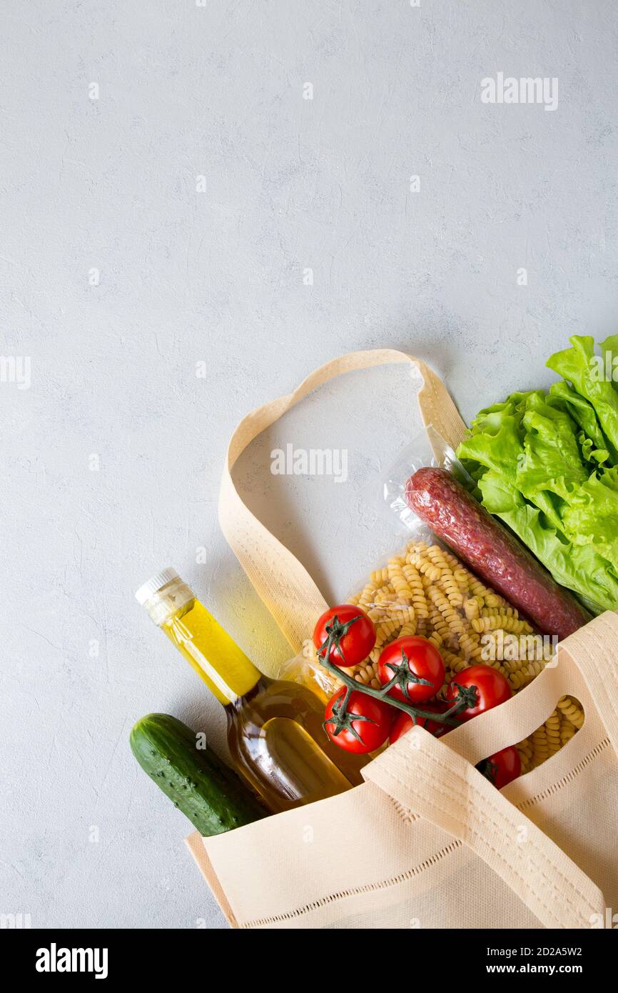 Ensemble de produits d'épicerie dans un sac à ficelle de pâtes, huile, salade, tomate, saucisse. Livraison d'aliments à domicile commandée en ligne sur fond gris. Ordre Internet de Banque D'Images