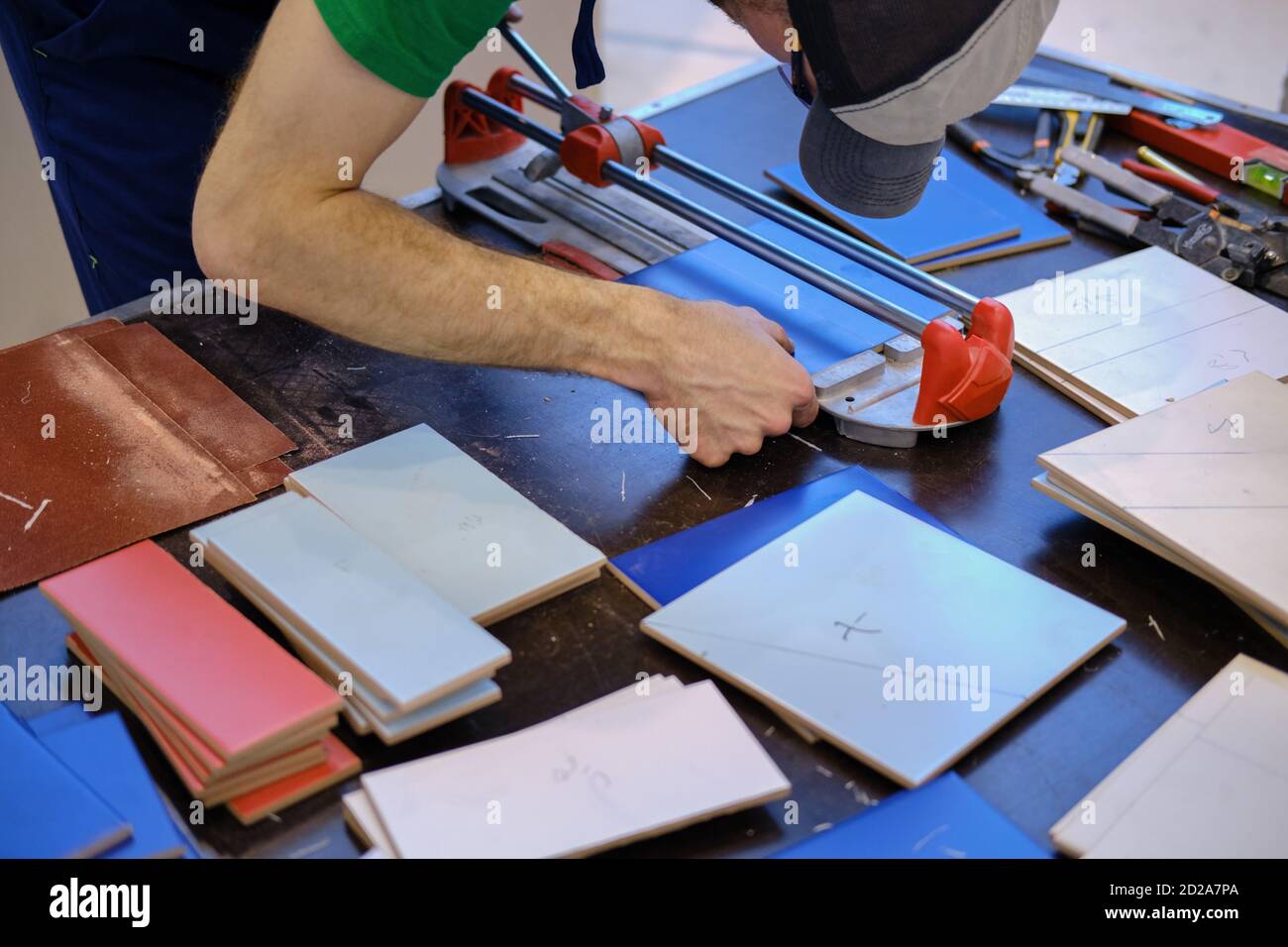 Les mains des hommes coupent les carreaux sur la table à l'aide d'un manuel fraise Banque D'Images