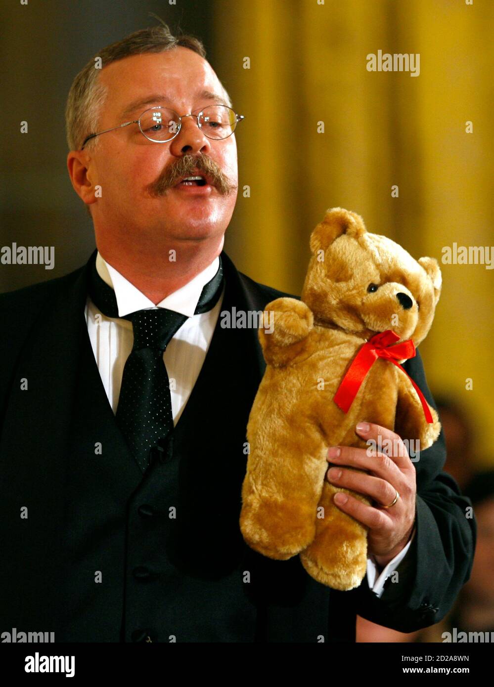 L'acteur Joe Weigand tient un « ours en peluche » alors qu'il dépeint le  président Theodore Roosevelt lors d'une conférence en l'honneur du 150e  anniversaire de Roosevelt dans la salle est de