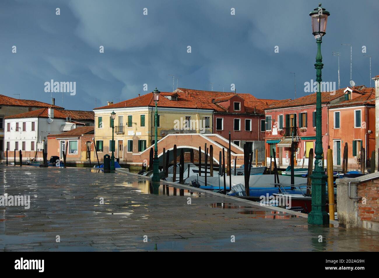 Venise, île de Burano, vue sur un canal dans l'après-midi lumière, ciel clair et sombre après une tempête, traditionnelles vénitiennes façades peintes reflet Banque D'Images