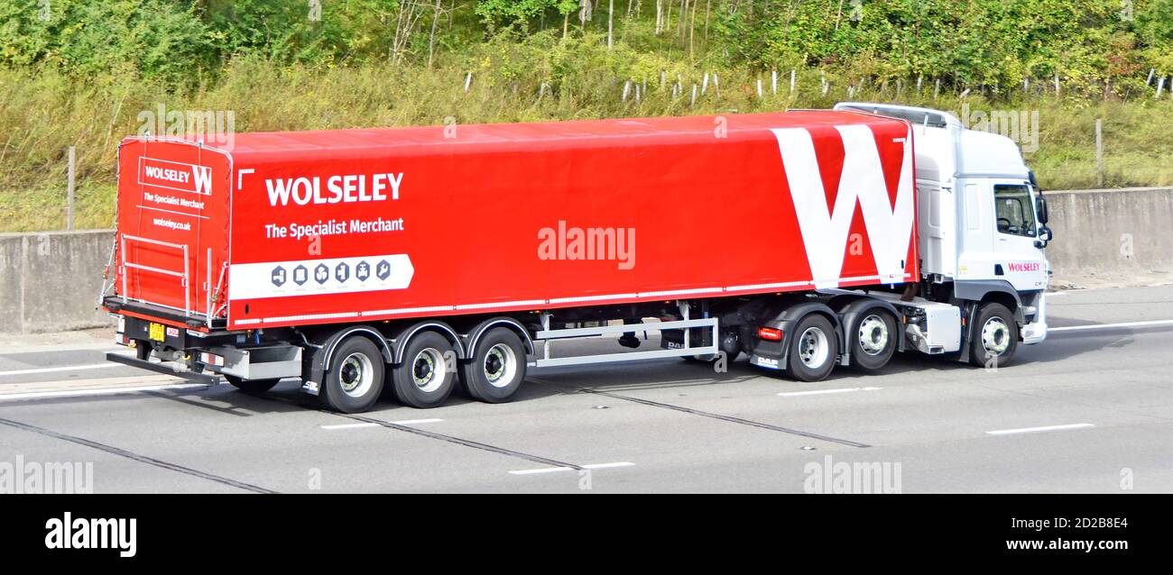 Wolseley plomberie spécialiste de la plomberie commerce remorque articulée rouge avec Logo remorqué par un camion Daff hgv blanc qui roule le long Autoroute britannique Banque D'Images