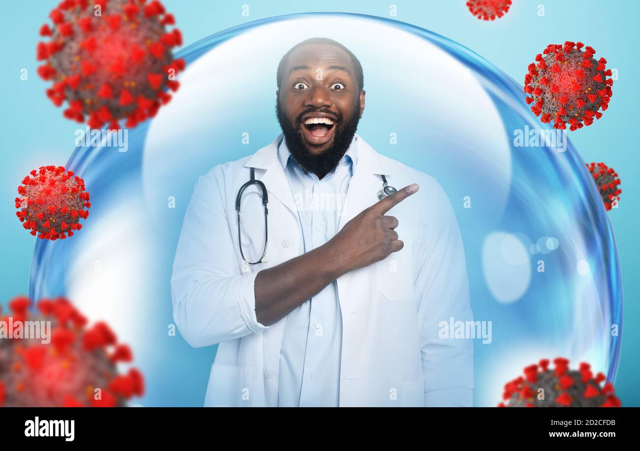 Le médecin souriant est heureux de gagner contre le coronavirus à l'intérieur d'une sphère de verre. Fond cyan Banque D'Images