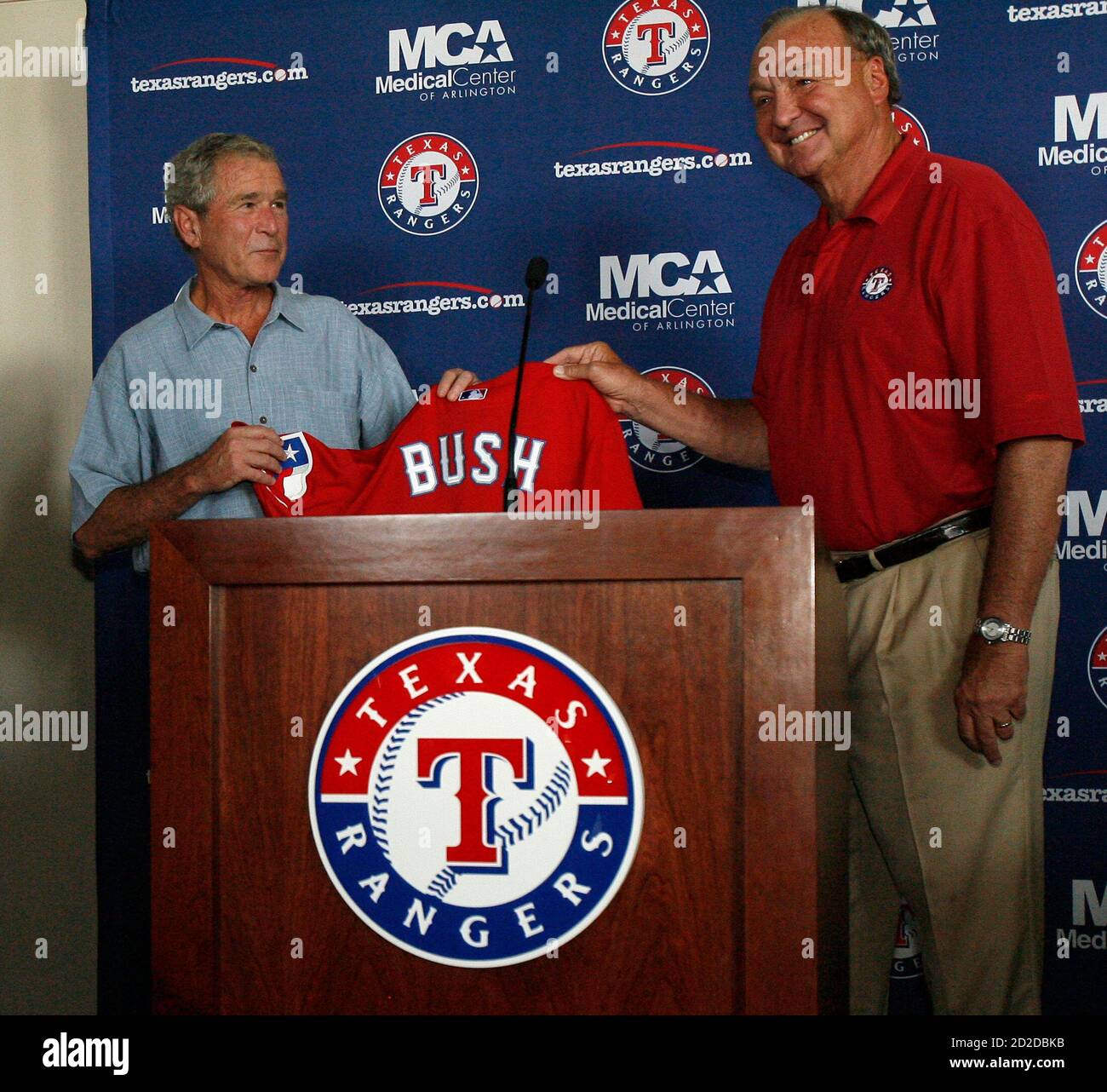 Former U.S. President George W. Bush (L) is presented a Texas Rangers  jersey from team owner Thomas Hicks at a dedication ceremony to rename the  owner's suite at Rangers Ballpark in Arlington