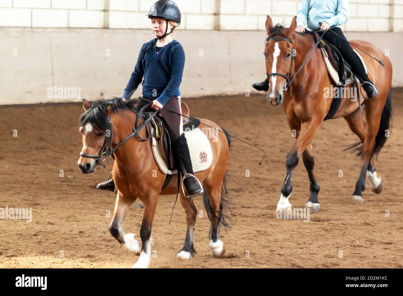 Amsterdam, pays-Bas 05/15/2010: Une jolie fille blonde en tenue d'équitation apprend à monter un cheval. Elle monte lentement un poulain brun à l'intérieur d'un train Banque D'Images