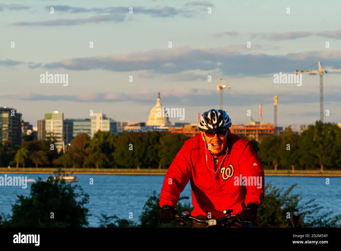 Washington DC, Etats-Unis 10/02/2020: Un cycliste portant un sweat à capuche de l'équipe de baseball des ressortissants de Washington est en vélo dans un parc urbain à Gravelly point à DC au soleil Banque D'Images