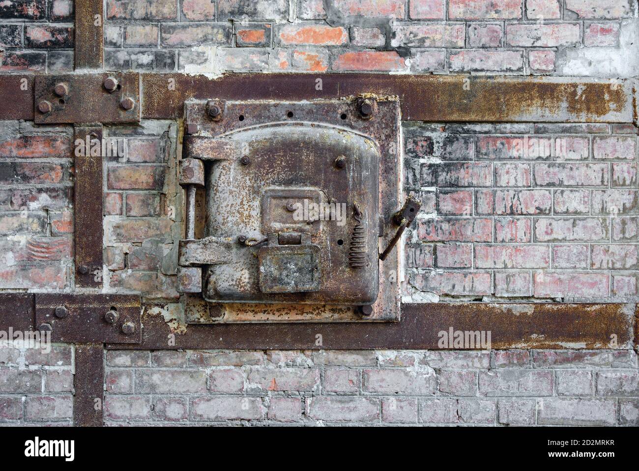 Vieux portillon en métal rouillé d'un four en brique rouge dans une usine abandonnée. Porte d'accès en métal rouillé avec cadre en métal boulonné à l'ancien mur en brique rouge. Banque D'Images