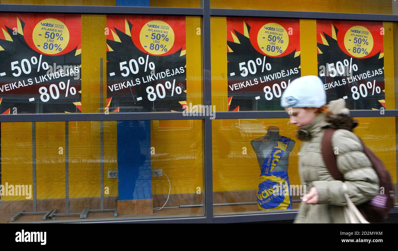 A girl walks past a shop window with posters announcing closing-down sales  in Riga February 17, 2009. Latvia should cut its economic forecast for this  year as a drop in the economy
