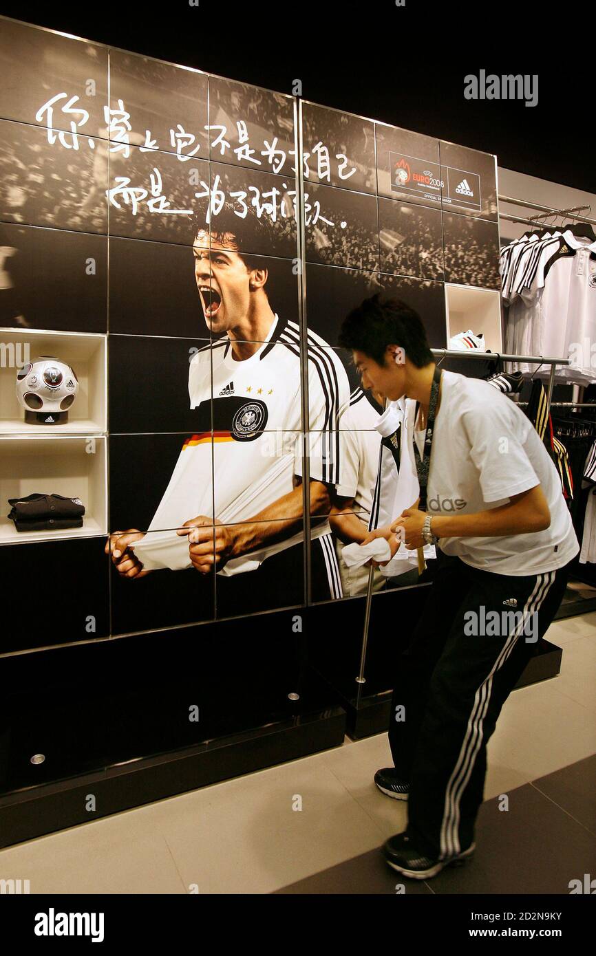 A Chinese staff arranges shirts near a poster of German national soccer  player Michael Ballack at the new and world's largest Adidas Brand Center  store in Beijing July 3, 2008. Adidas will
