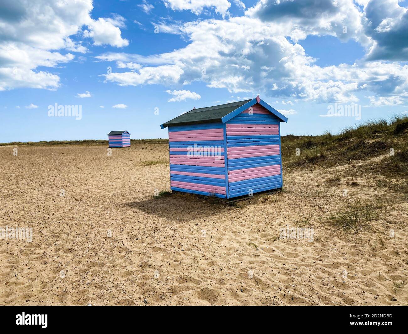 Cabanes de plage de Great Yarmouth en été, cabanes de plage traditionnelles britanniques sur une côte est anglaise, bandes horizontales bleues et roses, ciel avec nuages Banque D'Images