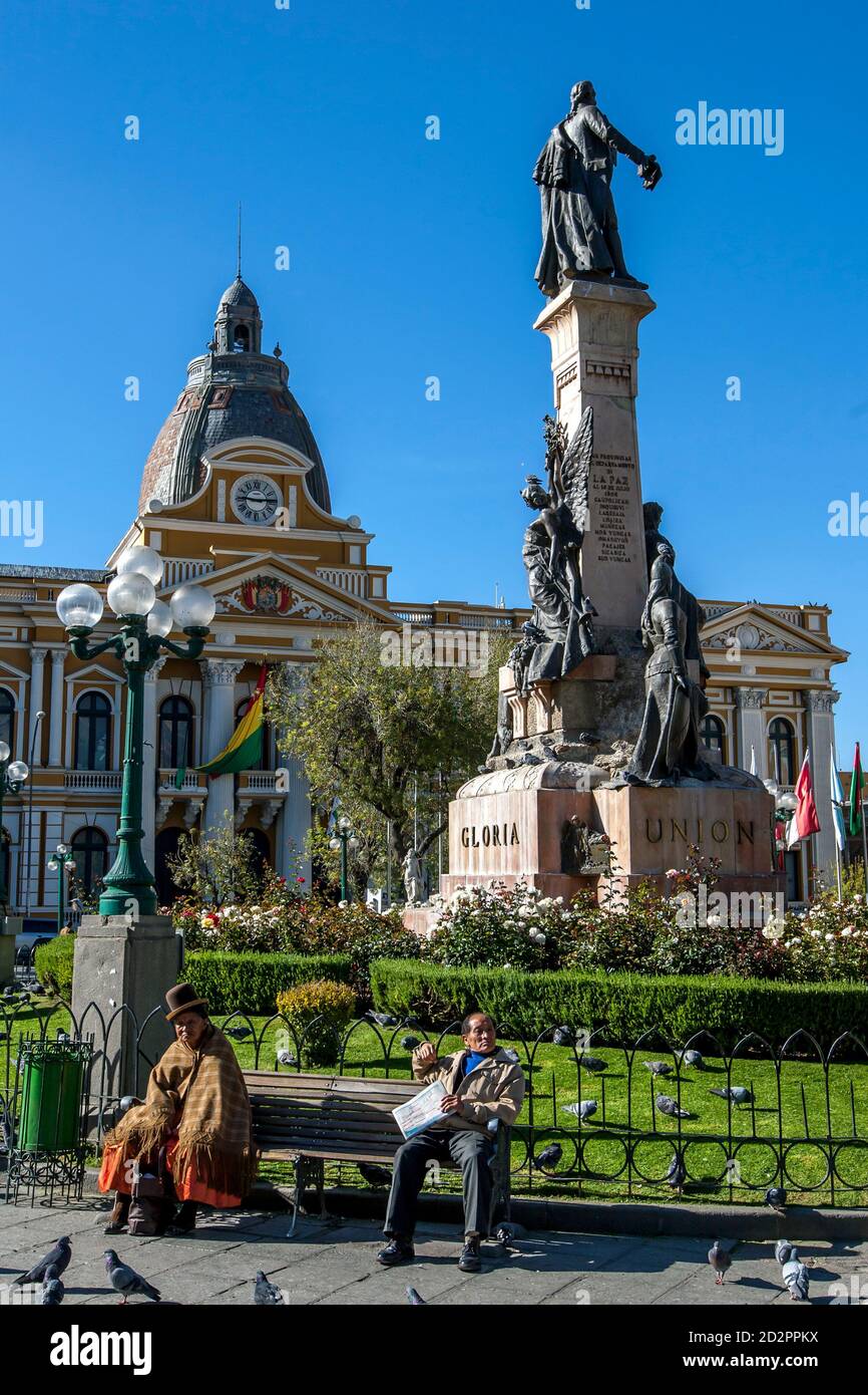 Les gens s'assoient sur un banc de parc à Plaza Murillo. En arrière-plan se trouve le beau Palais législatif de la Paz en Bolivie. Banque D'Images
