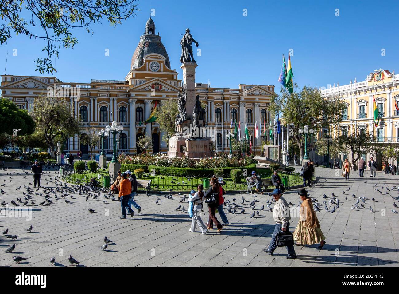 Les gens marchent devant un troupeau de pigeons dans la belle Plaza Murillo à côté du Palais législatif à la Paz en Bolivie. Banque D'Images