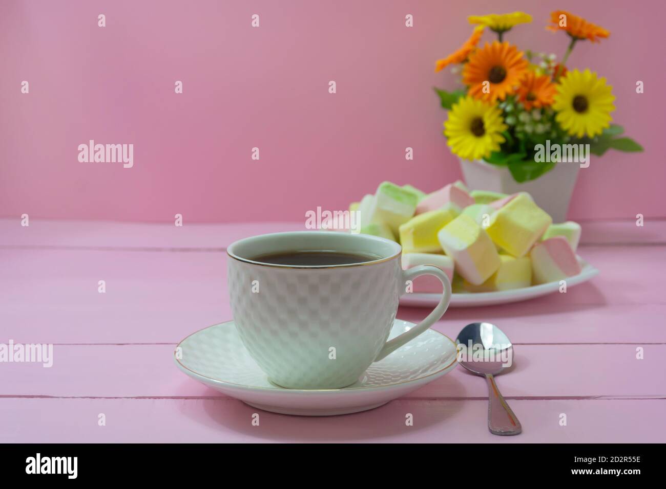 Tasse à café en gros plan sur fond de bois rose. Guimauves douces et bouquet de fleurs. Roma petit déjeuner concept, tendresse, Bonjour. Banque D'Images