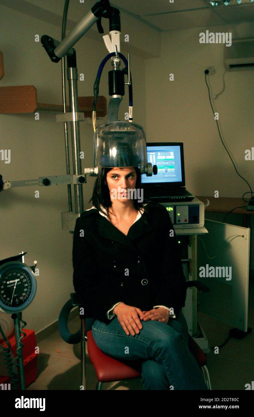 Un travailleur d'hôpital est assis sous un casque filaire tout en  démontrant un traitement expérimental pour la dépression clinique au Centre  de soins de santé mentale Shalvata dans la ville israélienne centrale