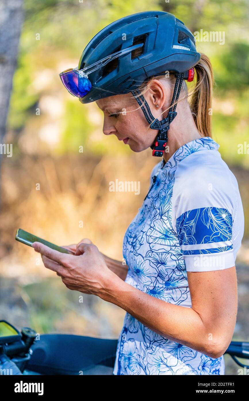 Vue rapprochée d'une femme dans des vêtements de sport et un casque de protection à l'aide d'un smartphone Banque D'Images