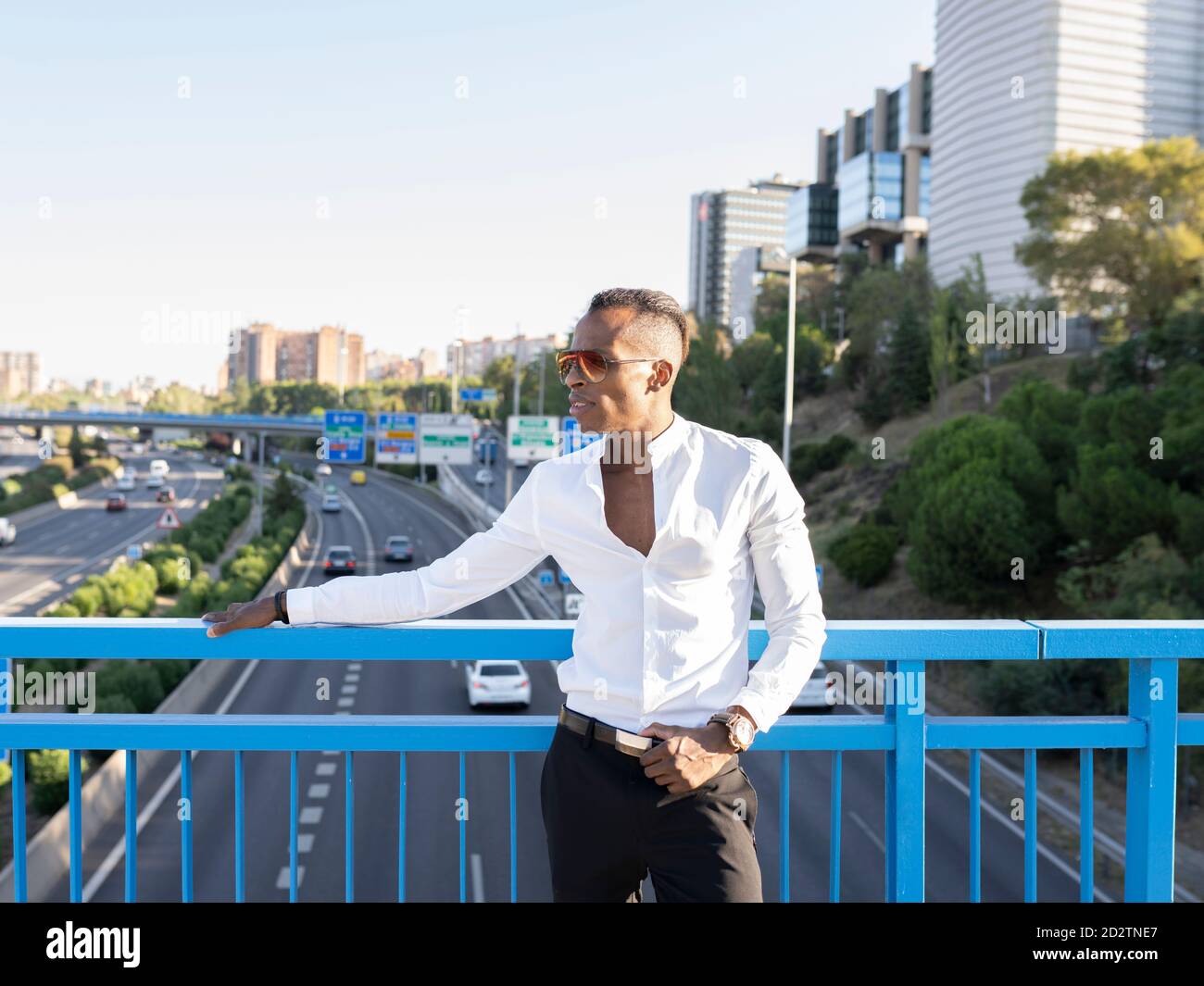 Homme d'affaires afro-américain déterminé en chemise blanche debout près garde-corps en métal sur le pont et en regardant loin Banque D'Images