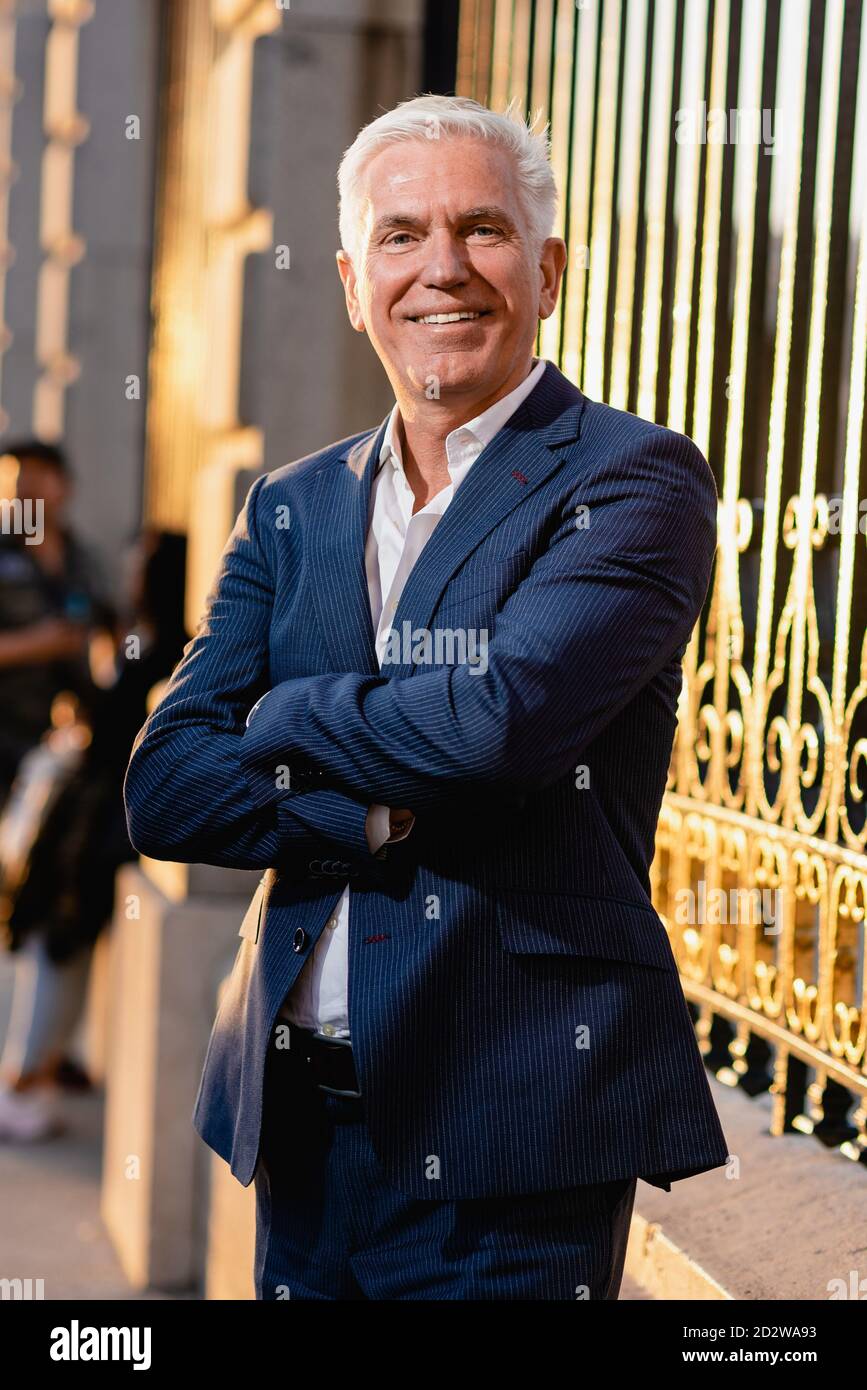 Happy Grey Hayant un senior Executive mâle dans un élégant costume bleu se tenir debout avec les bras croisés près de la clôture en métal et regarder appareil photo Banque D'Images