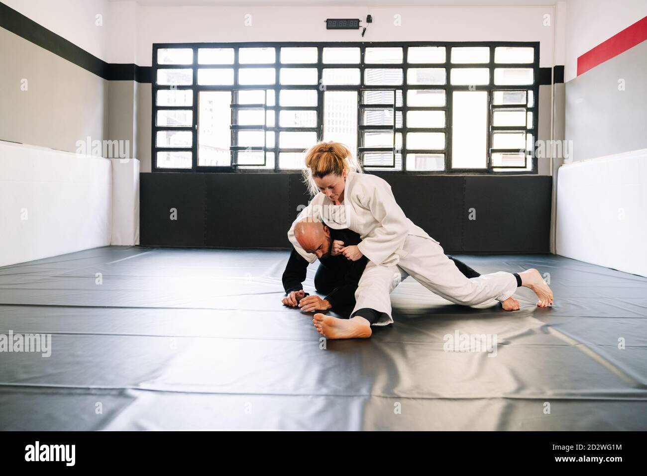 Homme et femme entrainement arts martiaux et judo avec kimonos sur le tapis  de sol de la salle de gym avec un étudiant qui regarde tout d'eux portant  un masque à cause