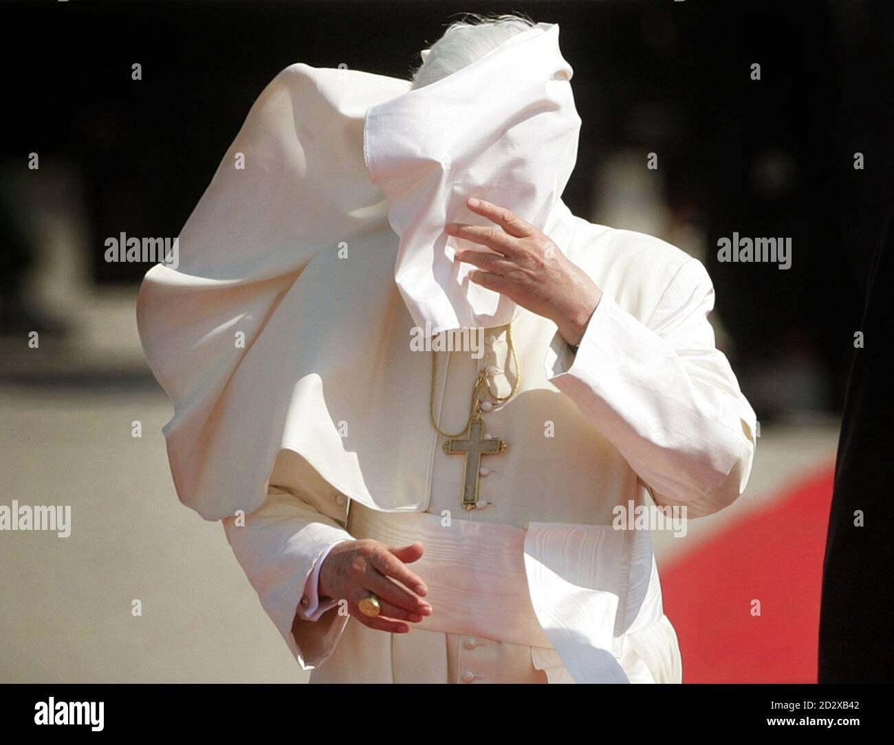 Pope Benedict XVI walks beside German President Horst Koehler (not  pictured) as heavy wind blows his cape into his face after his arrival at  Cologne's airport, August 18, 2005. Pope Benedict will