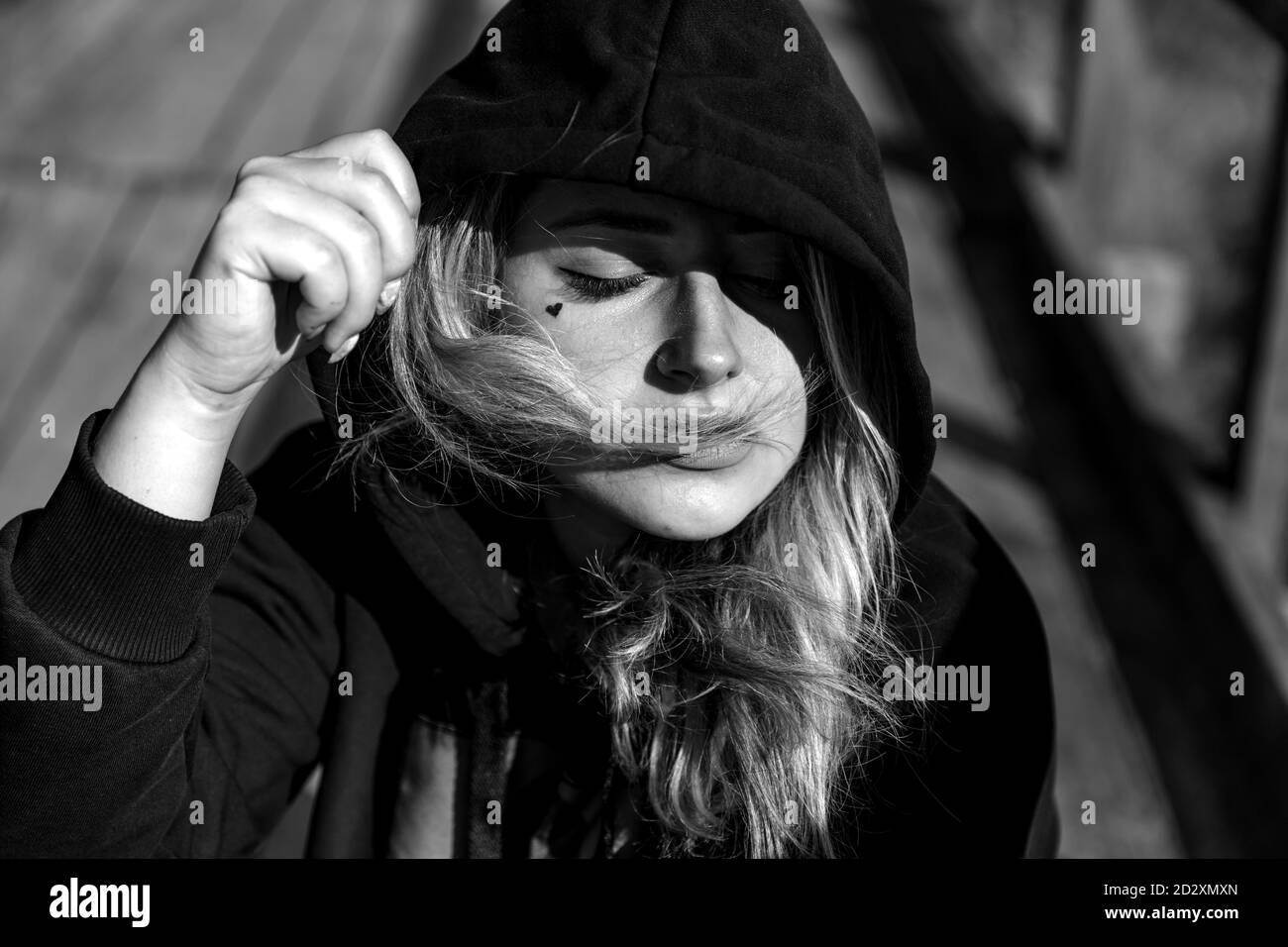 Portrait d'une adolescente en lunettes de soleil et un sweat à capuche noir à l'extérieur. Banque D'Images