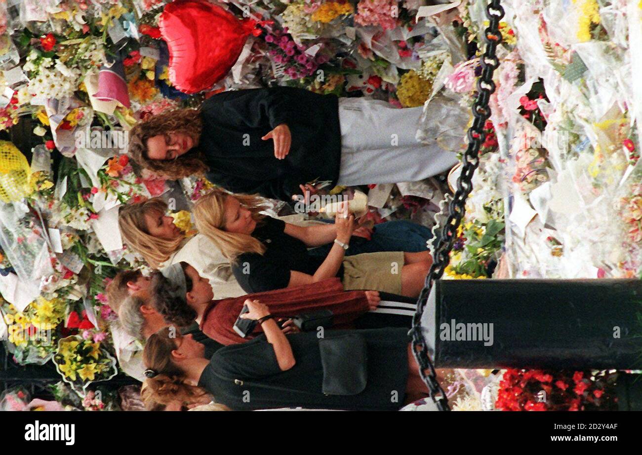 Membres pf le public regarde comme une jeune fille place une bougie parmi les hommages à la princesse Diana à la porte d'entrée de la maison Althorp dans le Northamptonshire. La princesse a été enterrée dans les terres de sa maison ancestrale hier. PHOTO DAVID JONES/PA Banque D'Images