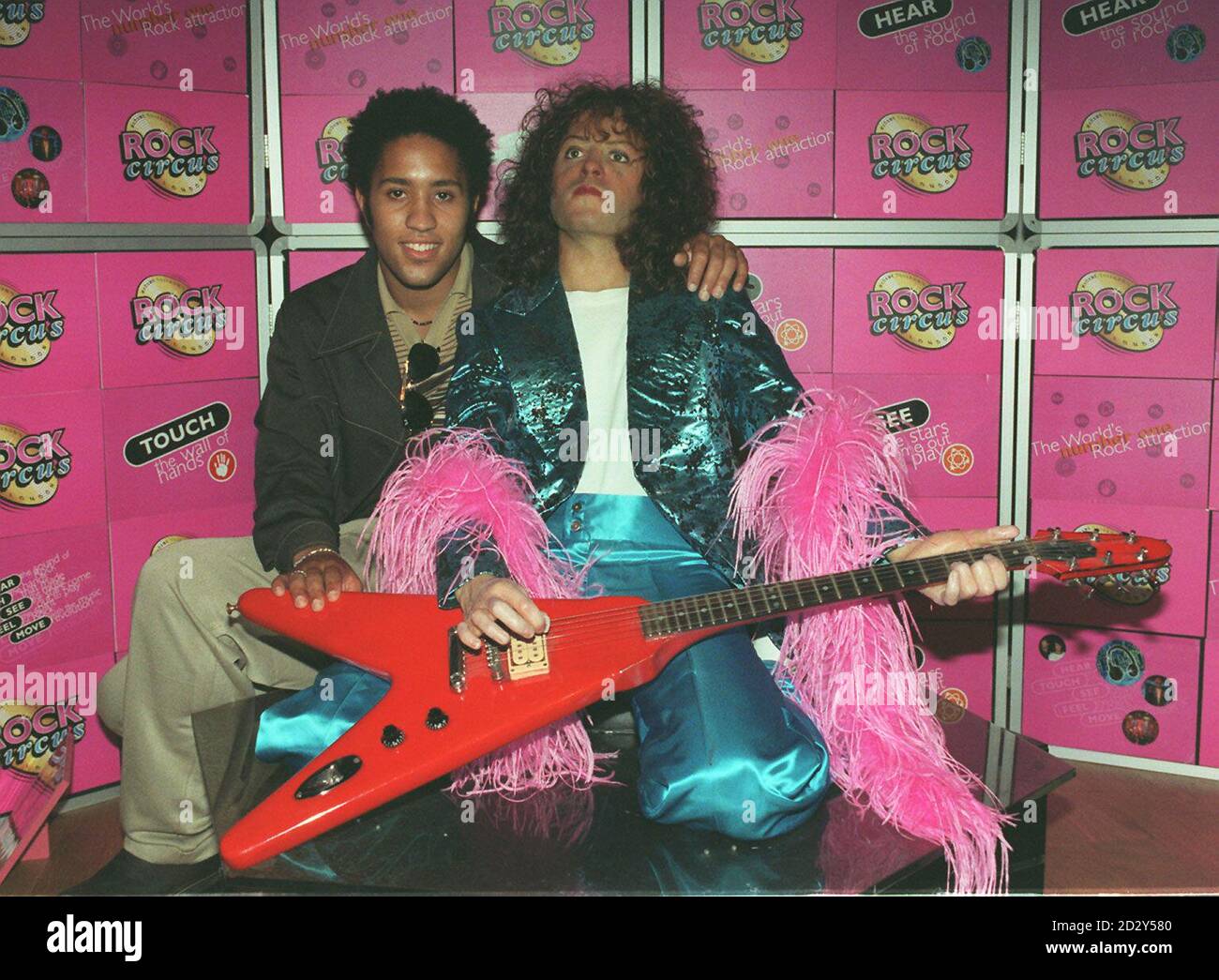 Rolan Bolan se présente face à face avec une image en cire de son père, Mark Bolan, star du rock des années 70, dans le hall de la renommée du Rock Circus de Piccadilly à Londres. * 13/9/02: Un buste en bronze grandeur nature du roi Marc Bolan de glam fut dévoilé aujourd'hui pour marquer le 25e anniversaire de sa mort. Son fils Rolan dévoilait le buste aux Memorial Gardens à quelques mètres de l'arbre où le préhomme T.Rex a été tué dans un accident de voiture à Barnes, dans le sud-ouest de Londres. Le frère de Bolan, Harry Feld, et les anciens bandits, Mickey Finn et Paul Fenton, devaient y assister. Banque D'Images