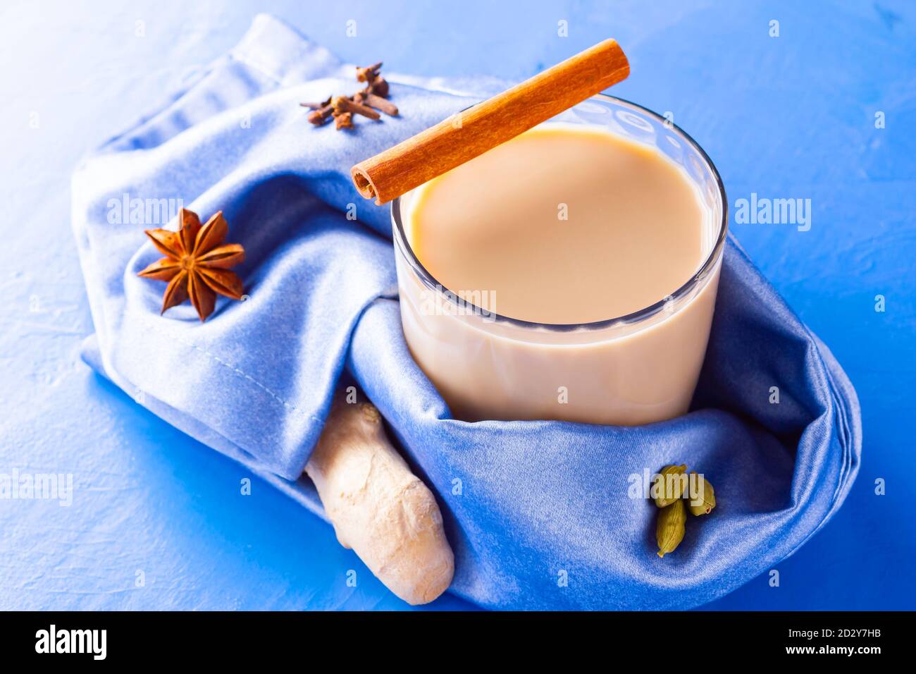 Thé Chai de masala. Boisson traditionnelle indienne - thé masala avec diverses épices. Verre de thé masala sur fond bleu Banque D'Images