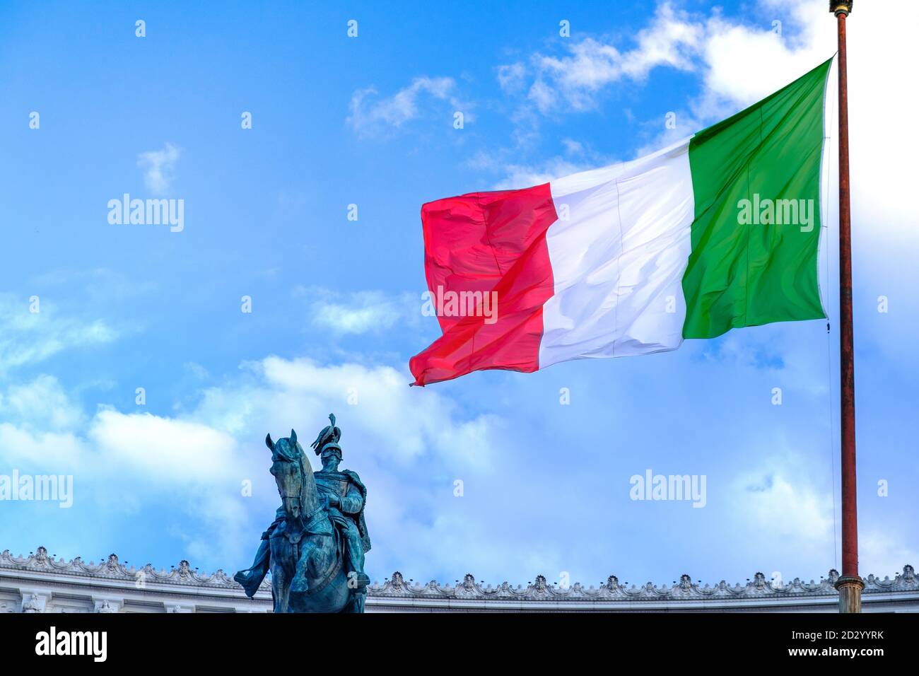 Drapeau italien agitant sur un ciel nuageux et une statue patriote sur le fond. Image symbolique de la Journée nationale italienne et de la Fête de la République le 2 juin Banque D'Images
