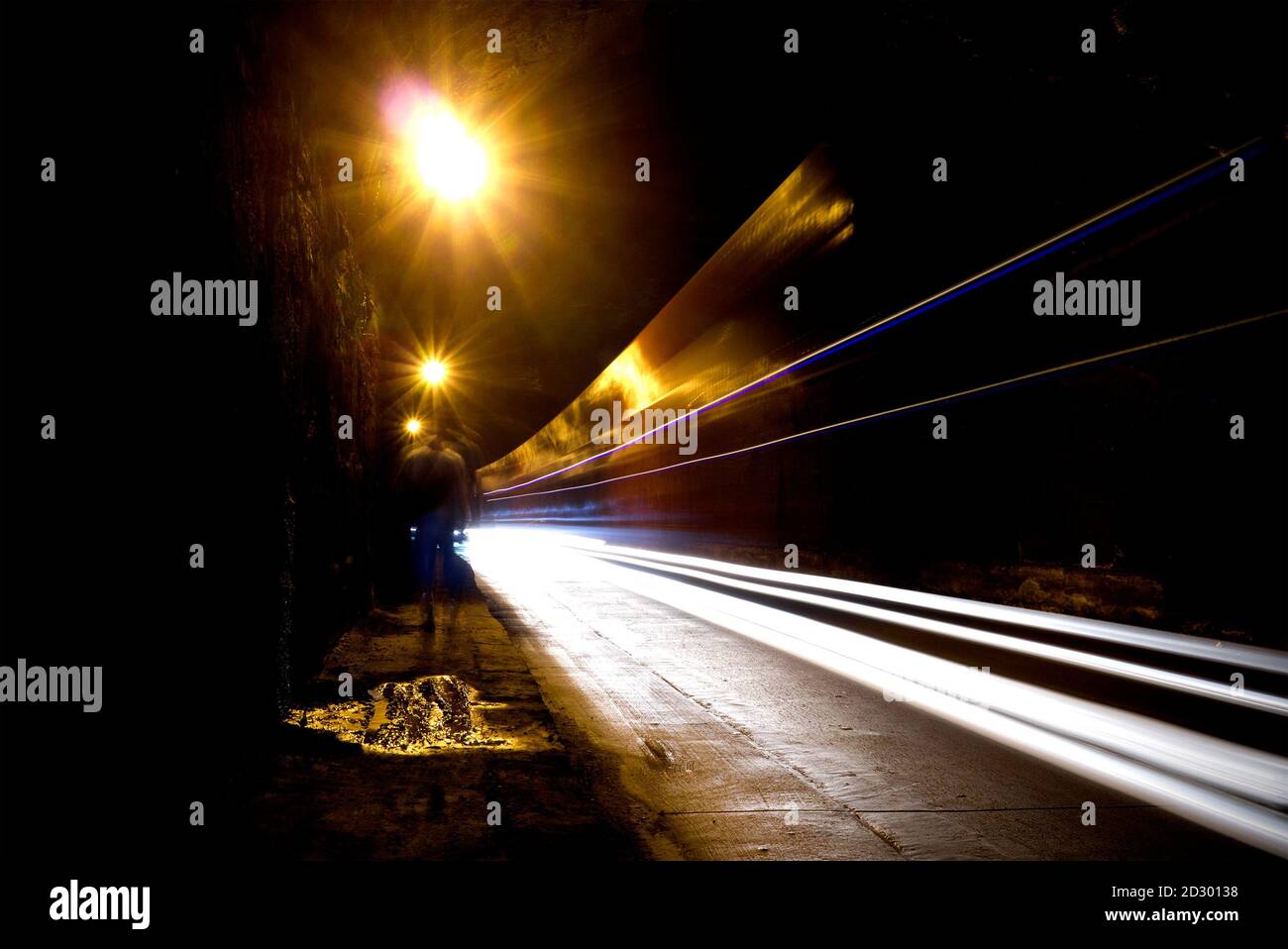 Image floue d'une silhouette humaine dans un tunnel. Un homme qui va à la lumière vive dans le flou. Banque D'Images