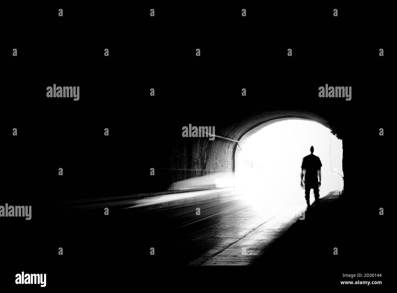 Image floue d'une silhouette humaine dans un tunnel. Un homme qui va à la lumière vive dans le flou. Banque D'Images