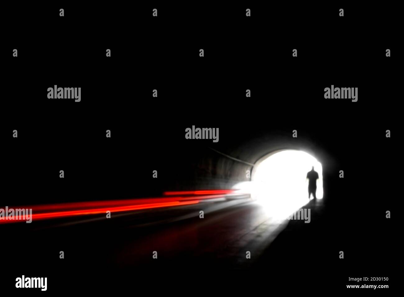 Image floue d'une silhouette humaine dans un tunnel. Un homme qui va à la lumière vive dans le flou. Banque D'Images