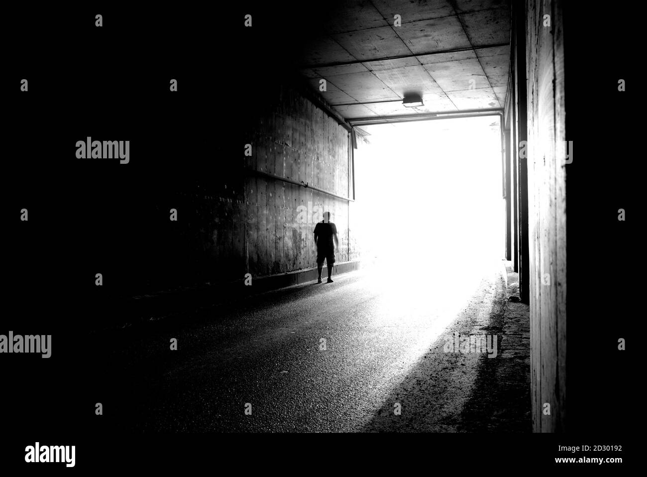 Image floue d'une silhouette humaine dans un tunnel. Un homme qui va à la lumière vive dans le flou. Banque D'Images
