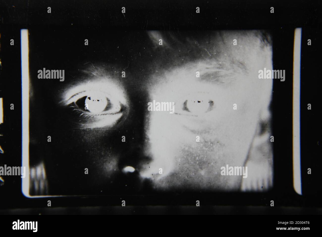Belle photographie en noir et blanc vintage des années 1970 d'un jeune regardant l'appareil photo avec des yeux brillants. Banque D'Images