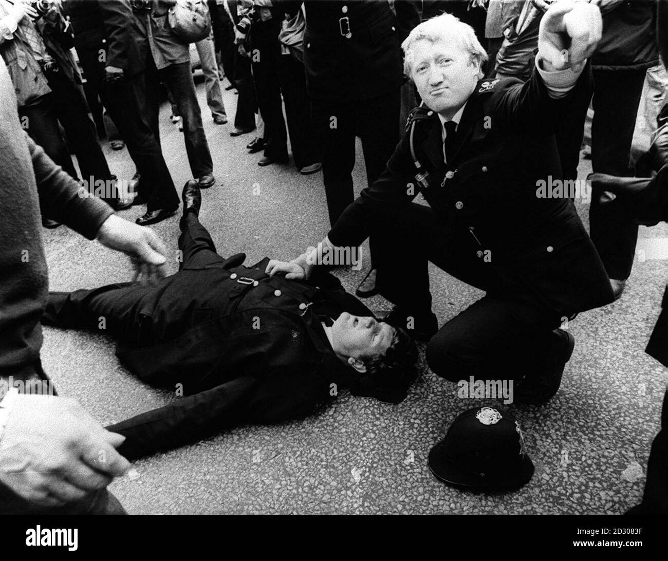 Un jeune officier de police, qui saignait fortement d'une blessure à la tête, est soigné par un collègue après avoir été frappé à la tête par une bouteille devant l'usine assiégée de traitement de film Grunwick dans le nord de Londres, lors d'un affrontement entre la police et les piquets de grève. * les affrontements ont été déclenché par l'arrestation du chef des mineurs du Yorkshire, Arthur Scargill. Banque D'Images