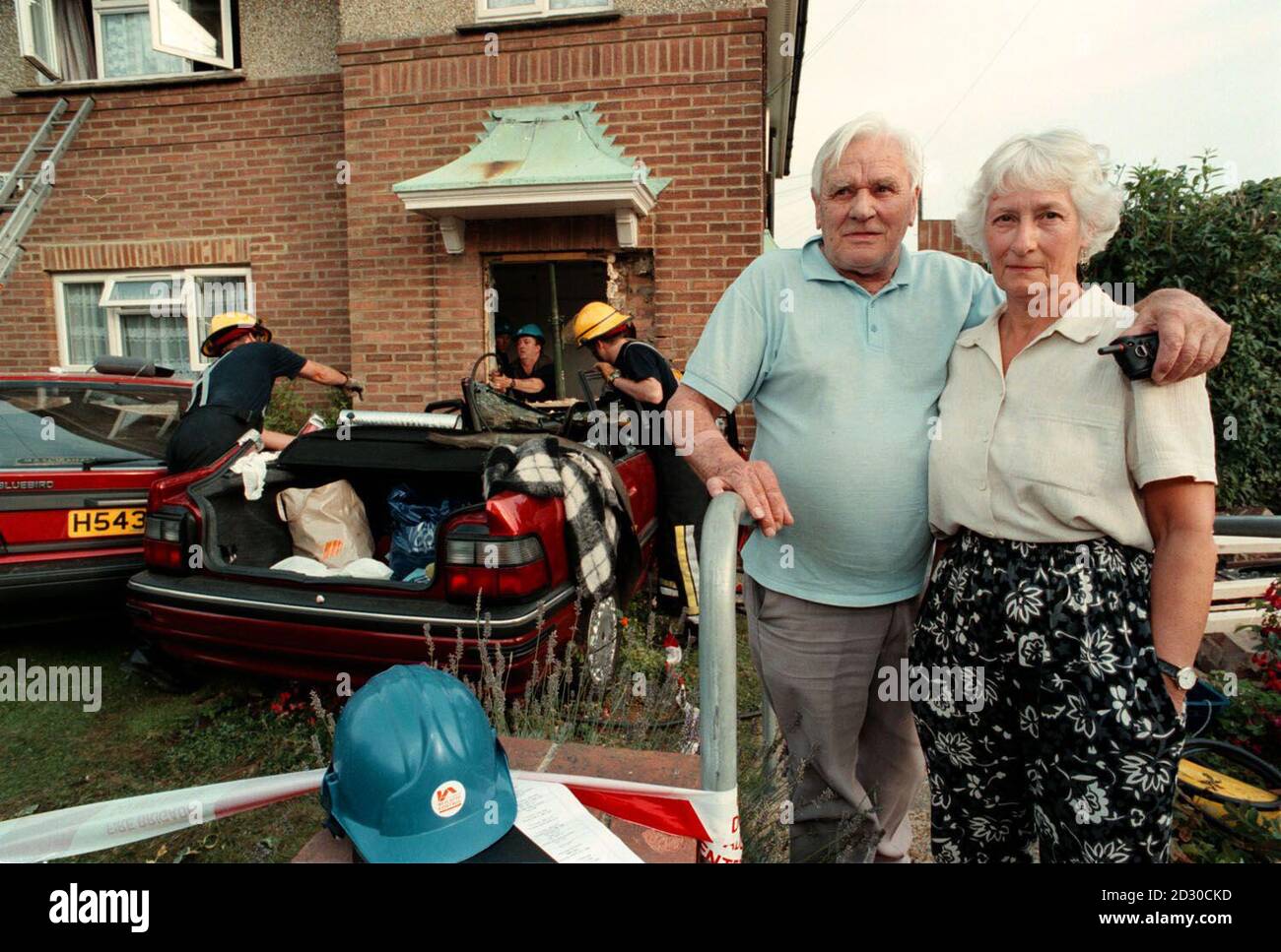 Geoffrey et Dorothy Hayler, résidents de l'appartement à l'étage, regardent comme des pompiers qui vérifient une voiture à Downland Drive après que la voiture contenant trois femmes âgées a labouré par la porte avant d'un appartement.* les services d'urgence ont été alertés après que le Rover automatique s'est écrasé dans une voiture garée et a écrasé le deuxième véhicule dans le mur sous une fenêtre du premier étage, le Rover s'est embarqué dans la porte avant, où il a mis la terre à un arrêt.Les pompiers ont coupé le conducteur et le passager avant de l'épave, et les trois femmes du Rover ont été emmenées en ambulance dans le comté de Brighton, dans le comté de Royal Sussex Banque D'Images