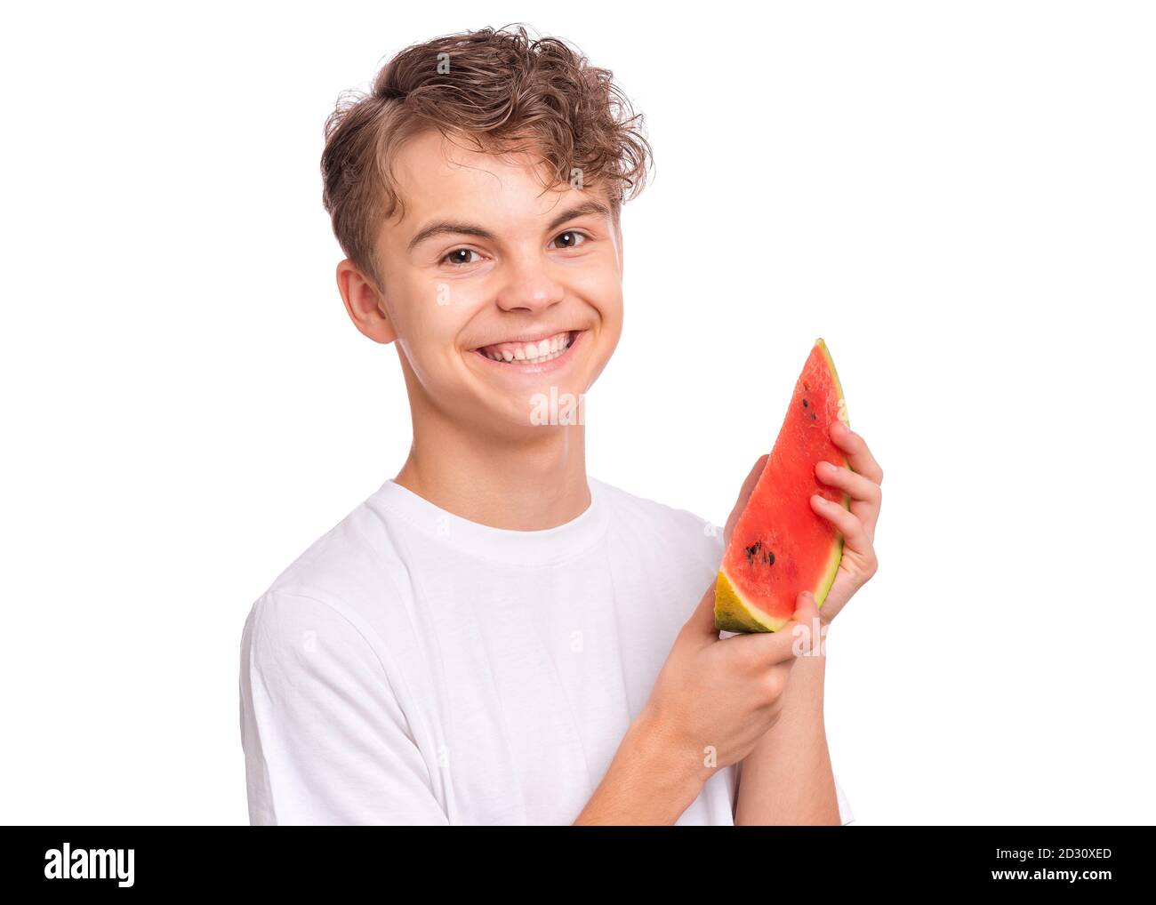 Portrait d'un jeune garçon mangeant une pastèque juteuse mûre et souriant. Banque D'Images