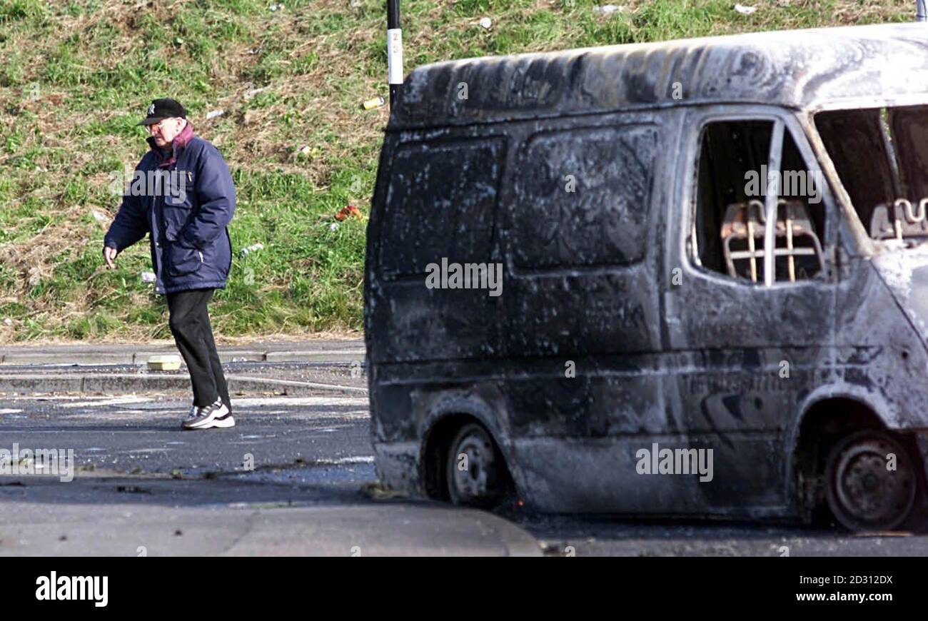 Un homme passe devant une camionnette brûlée après une nuit d'enracinement dans Newtownabbabbabbabbabbabbabbabbatiale située à l'extérieur de Belfast, en Irlande du Nord.Les émeutes se sont poursuivies dans des zones loyalistes autour de la province britannique après le défilé banni de Drumcree. Banque D'Images