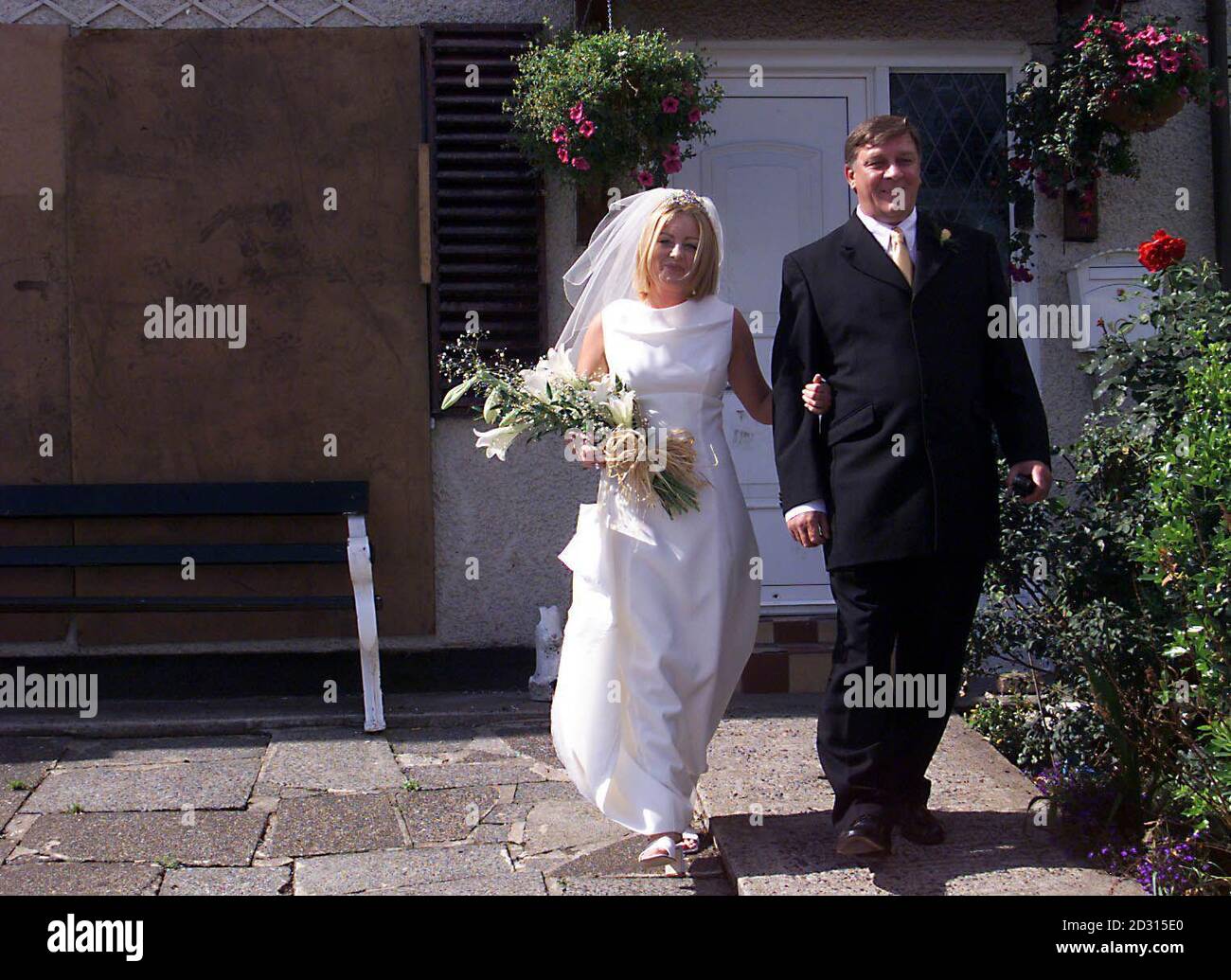 Winston Rea descend le chemin du jardin de sa maison naufragé dans la région de Shankill à Belfast, avec sa fille Pauline, 21 ans. L'éminent loyaliste de 49 ans, a été brûlé hors de sa maison pendant la querelle entre l'UDA et l'UVF. * il est retourné à la maison pour qu'il puisse escorter sa fille de la maison familiale à son mariage. La famille Rea était parmi plus de 50 forcés de fuir leurs foyers pendant la querelle. Banque D'Images