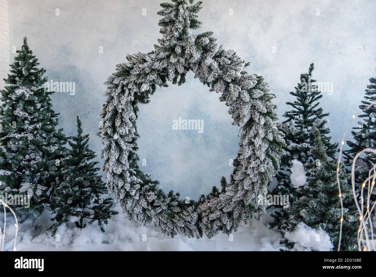 Un anneau enneigé d'aiguilles d'épicéa contre un ciel bleu avec des arbres de Noël dans une guirlande lumineuse. Place pour les publicités et le texte. Copier l'espace Banque D'Images